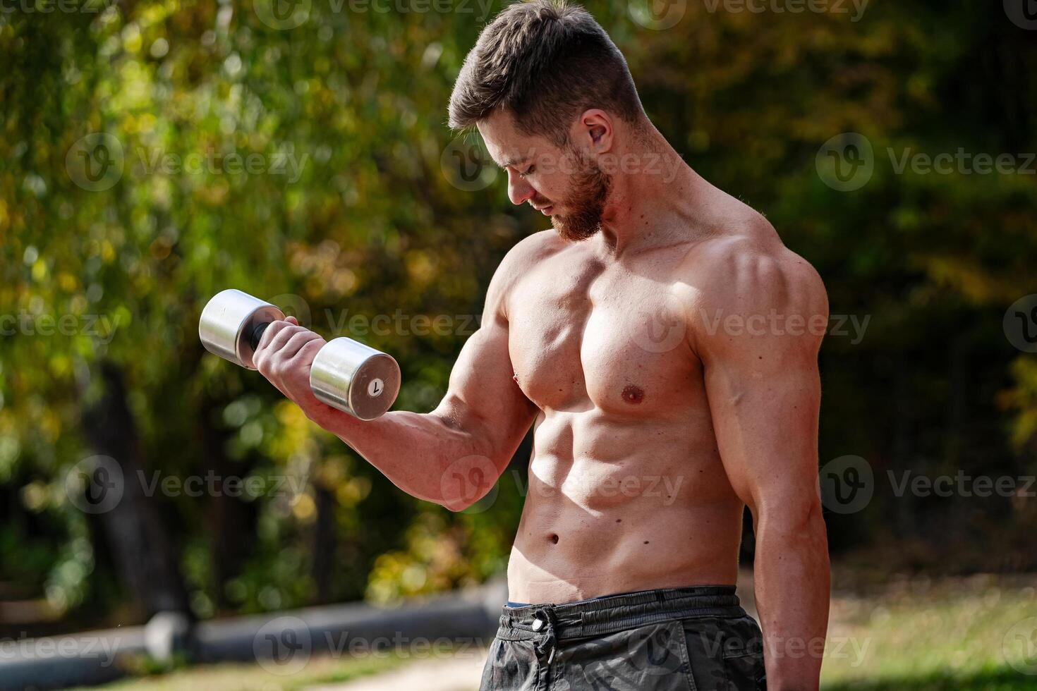 Shirtless sporty male body. Muscular young body making biceps exercise. photo