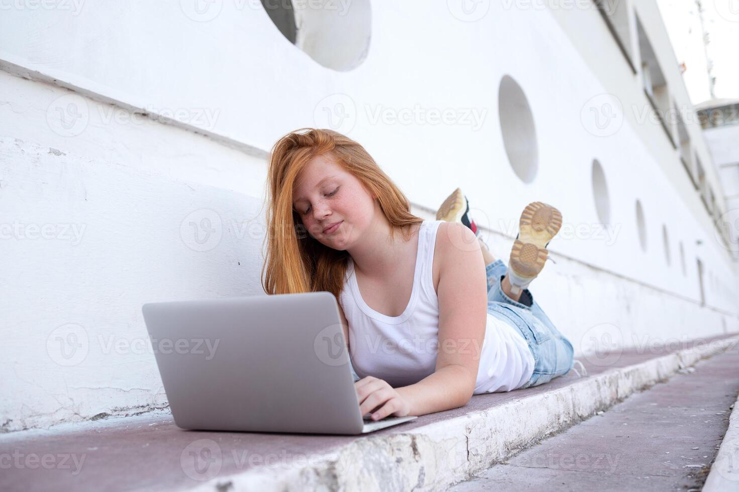 teenage girl working on laptop sitting on steps photo