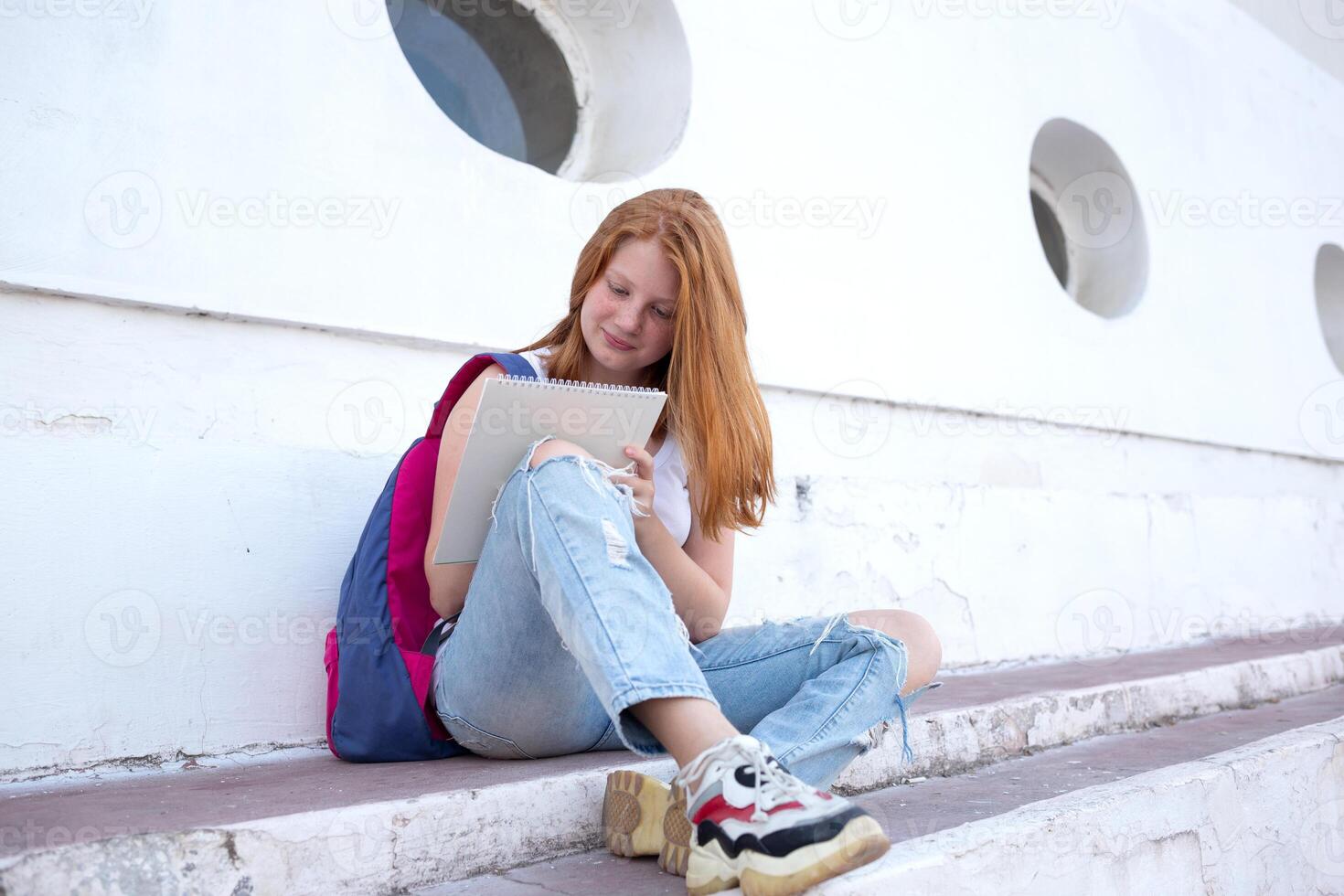 teenage girl draws in the sketchbook while sitting on the steps photo