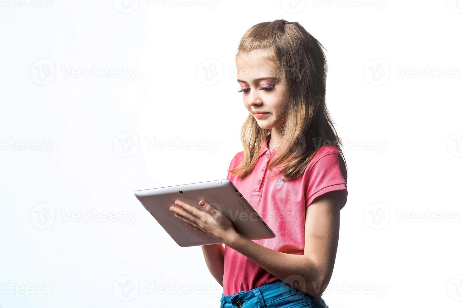 Beautiful little girl with a tablet computer in hands on a white background. Emotions of the child. photo