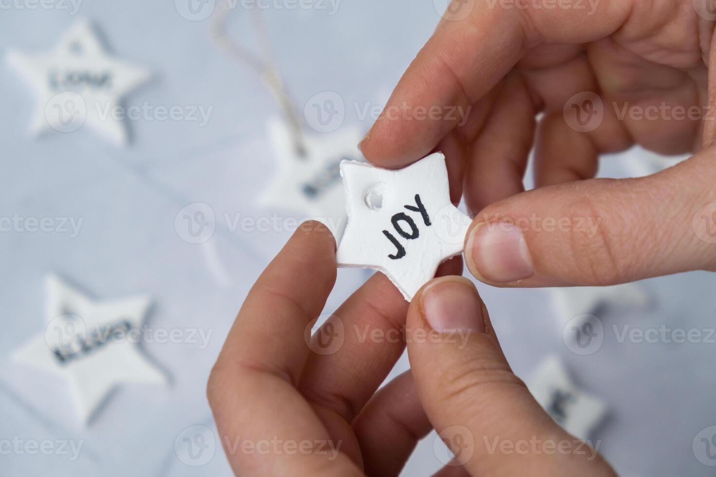 Christmas star with word JOY Creator is using white air dry clay for making decor to Christmas tree holiday. Creating hobby recreation activity that involves fingers. DIY crafting Modern art photo