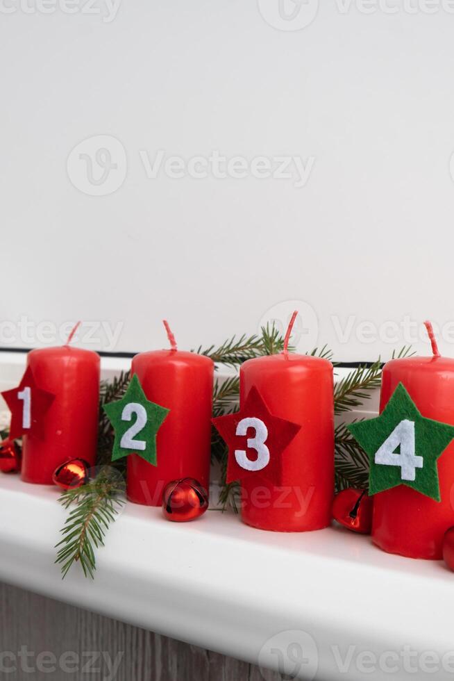 New year and Christmas preparation. Four red advent candles with numbers in white windowsill. Handmade eco-friendly decor. Sustainable Christmas decoration. Copy space photo