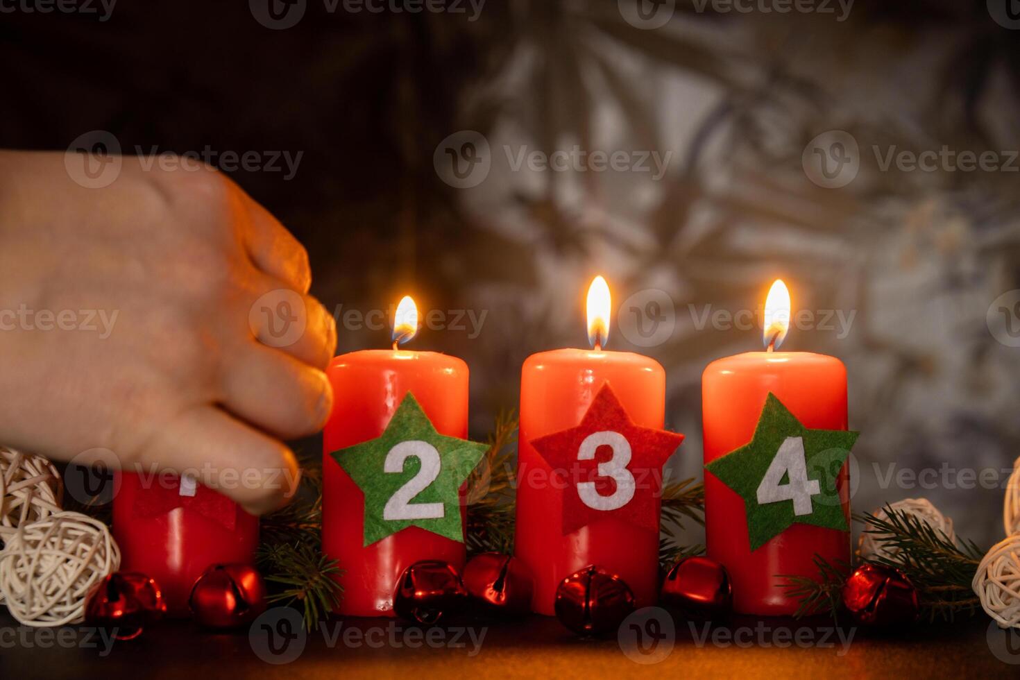 Four Advent red candles with numbers burning, fir branches and Christmas zero waste decorations in dark room in evening. Holiday preparation copy space for text. Catholic traditions of Christmas new year winter holidays photo