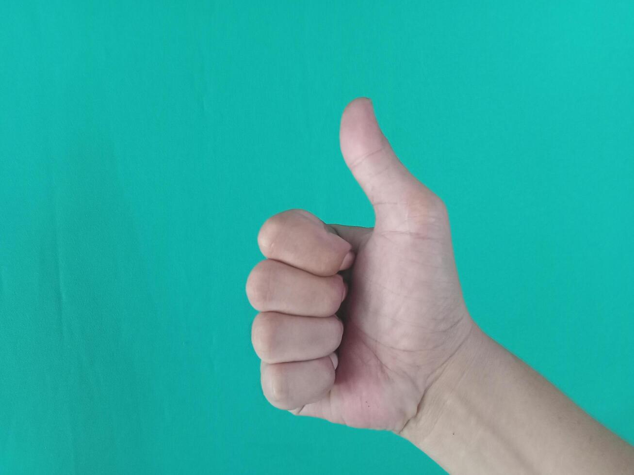 Thumbs up gesture, horizontal view, green background photo