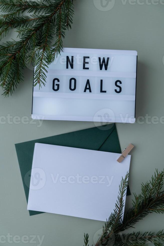 Lightbox with inspirational message NEW GOALS with fir branches on pastel background. Happy new year promises resolutions concept. Copy space envelope mock up sample Self growth and personal development photo