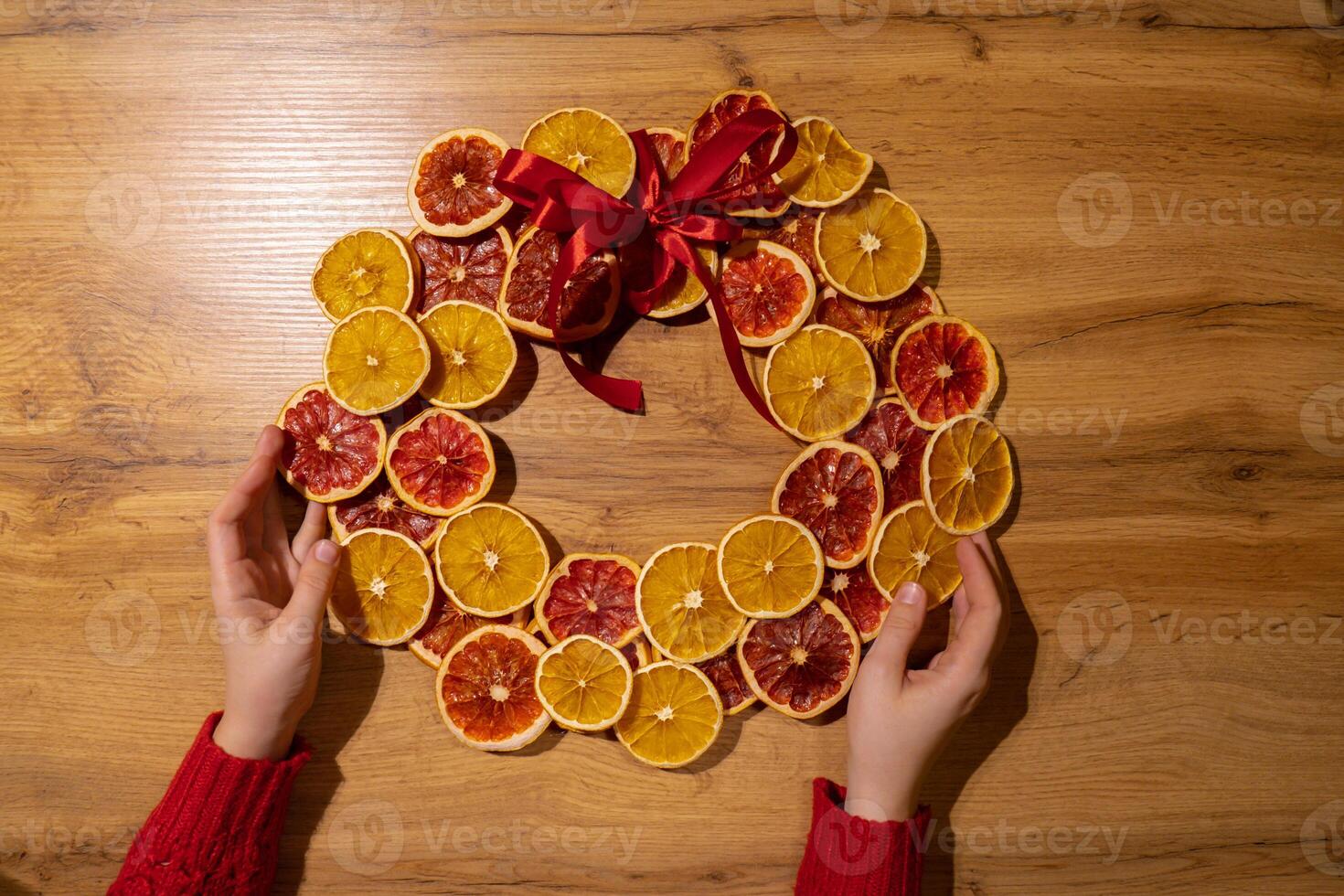 Step by step instruction of making handmade Christmas wreath made of dry fruits oranges and grapefruits. Female hands creating craft homemade decor. New year celebration. Winter holidays photo