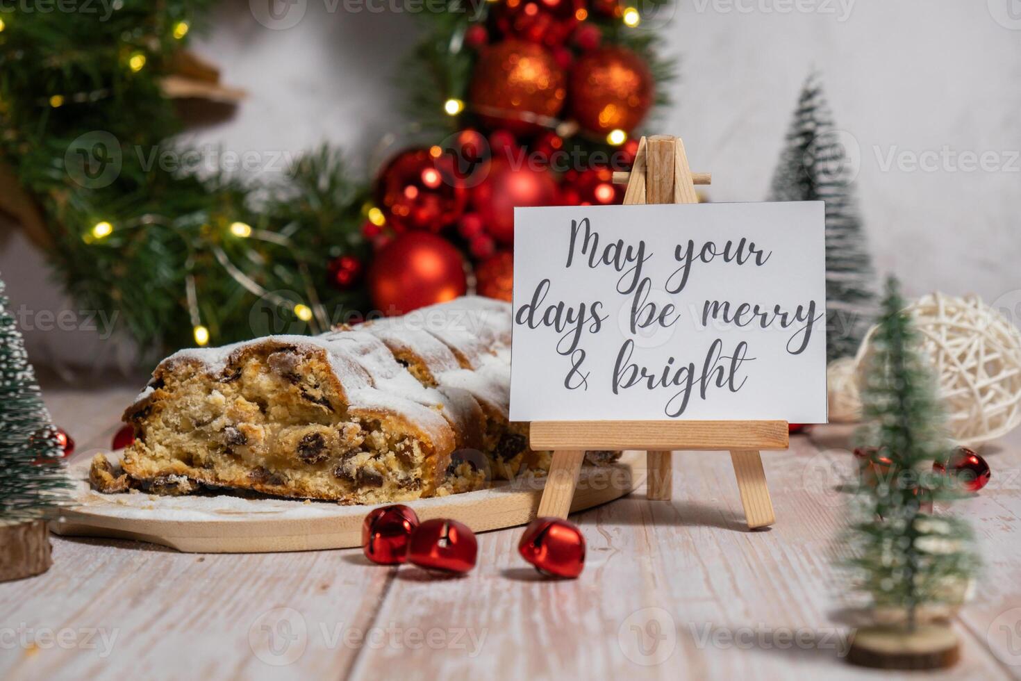 Greeting card with message MAY YOUR DAYS BE MERRY AND BRIGHT congratulations. Christmas Stollen in Christmas lights and decoration. Traditional sweet fruit loaf with icing sugar festive pastry dessert. Holiday baking food concept. photo