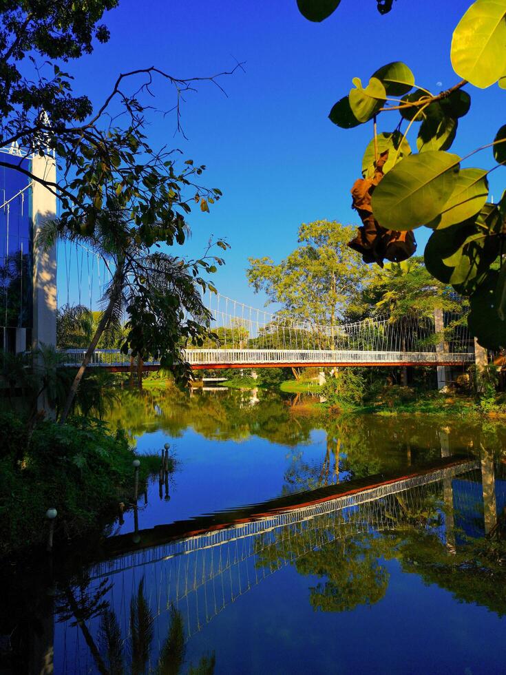 Pedestrian footbridge with reflection in still water on a bright sunny day, Nimman, Chiang Mai, Thailand, 2024 photo