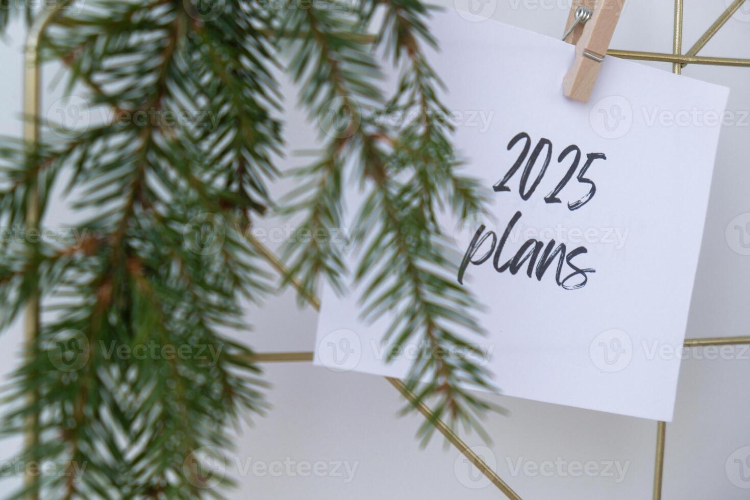 2025 PLANS text on white paper note on vision board with Christmas decor. New year aims resolutions. New me you concept visualizing dreams photo