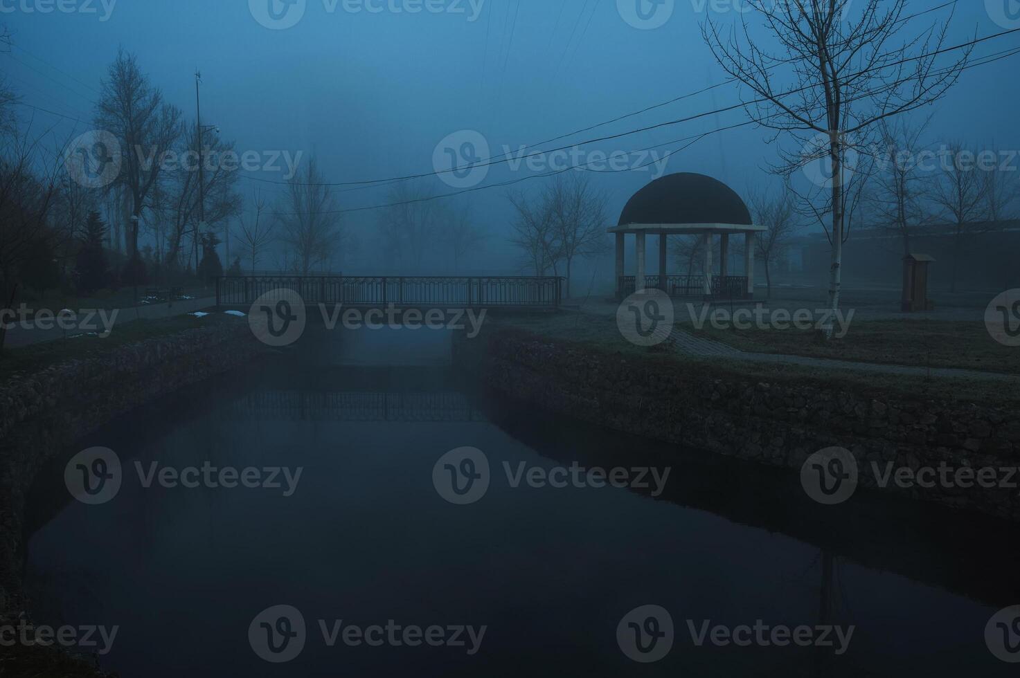 misty landscape with a gazebo by river on an autumn morning in the fog mist photo