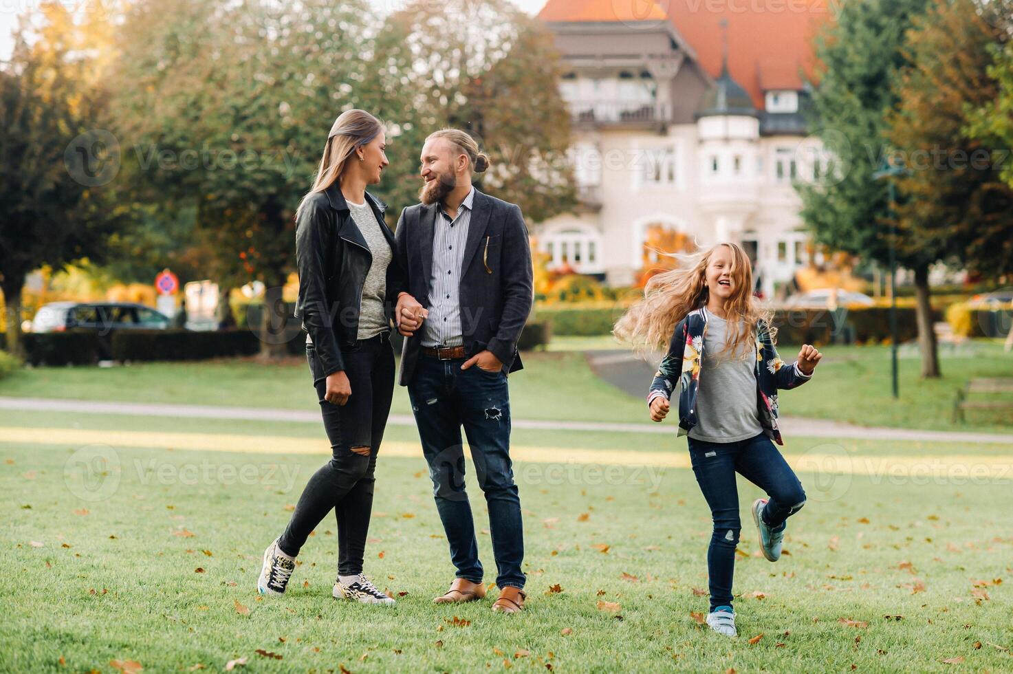 A happy family of three runs through the grass in Austria's old town.A family walks through a small town in Austria.Europe.Velden am werten Zee photo
