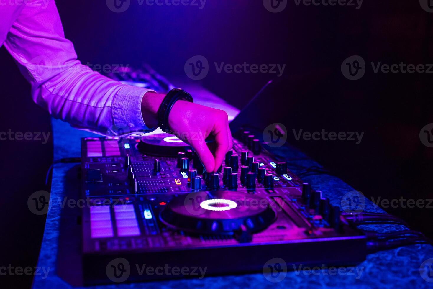 DJ plays music with his hands on a mixer controller photo