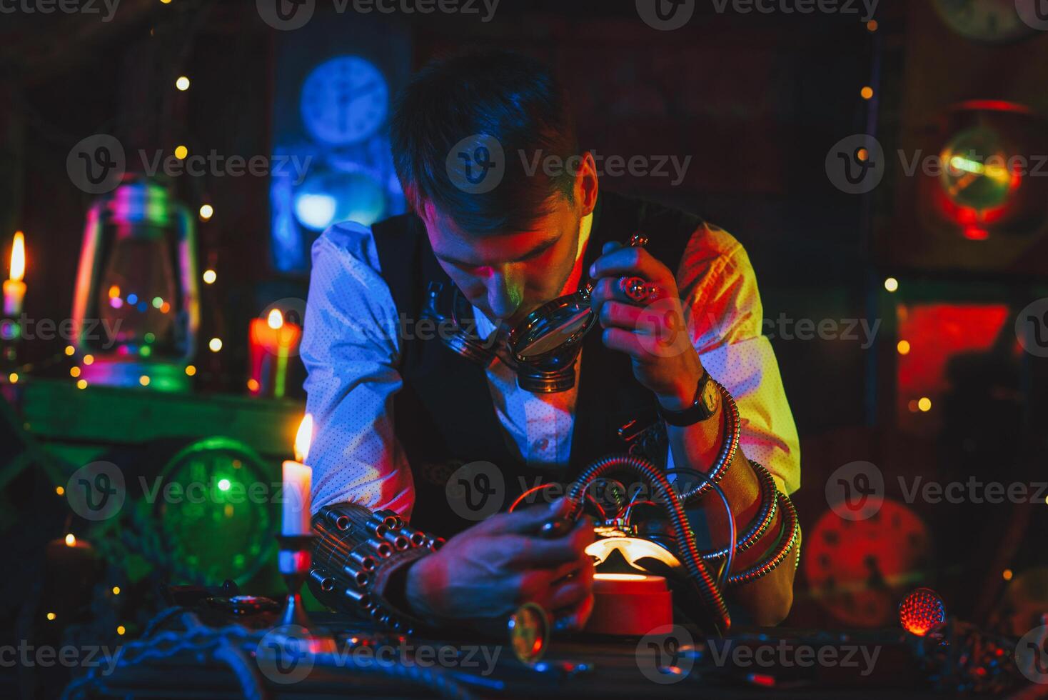 male inventor in a steampunk suit repairs the mechanism. A watchmaker with tools and a magnifying glass works photo