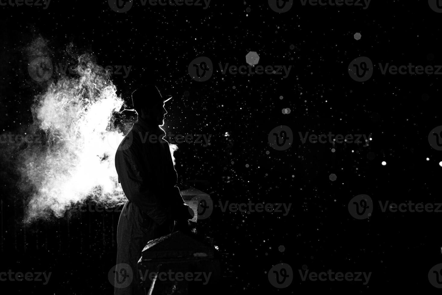 dramatic silhouette of a dangerous man in a hat at night in the rain in the city photo