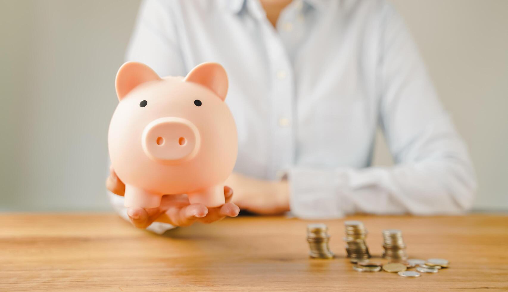 Hand holding piggy bank on wood table. Save money for wealth, financial investment business, future education concept with copy space for input text. photo