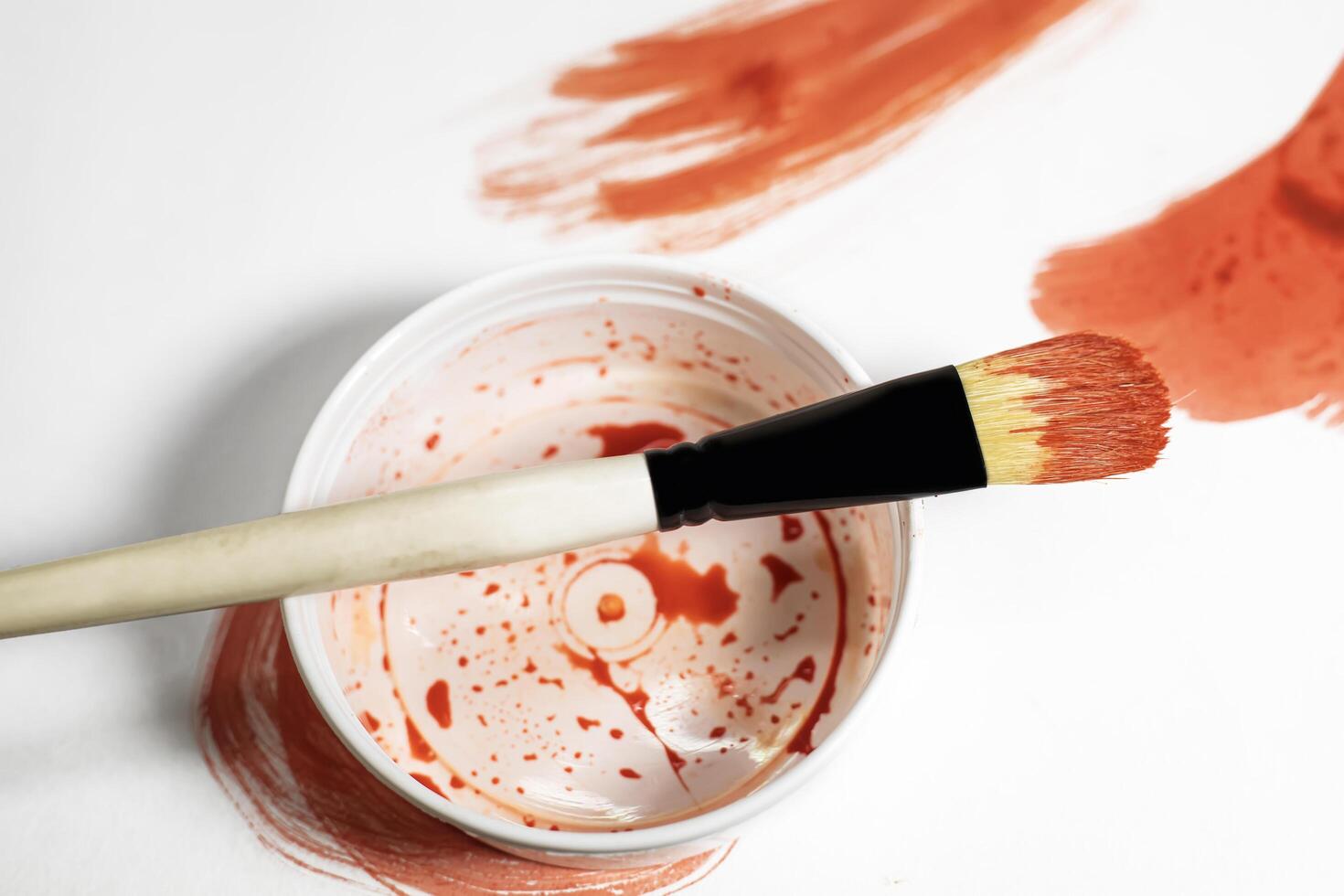 Paint brush on top of paint can with red paint on white background. Top view photo