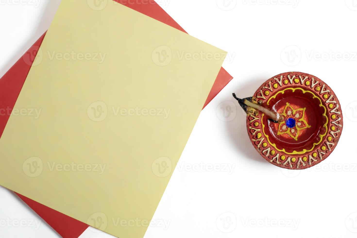 Handmade clay diya lamp with blank greeting card for Diwali festival greetings on white background photo