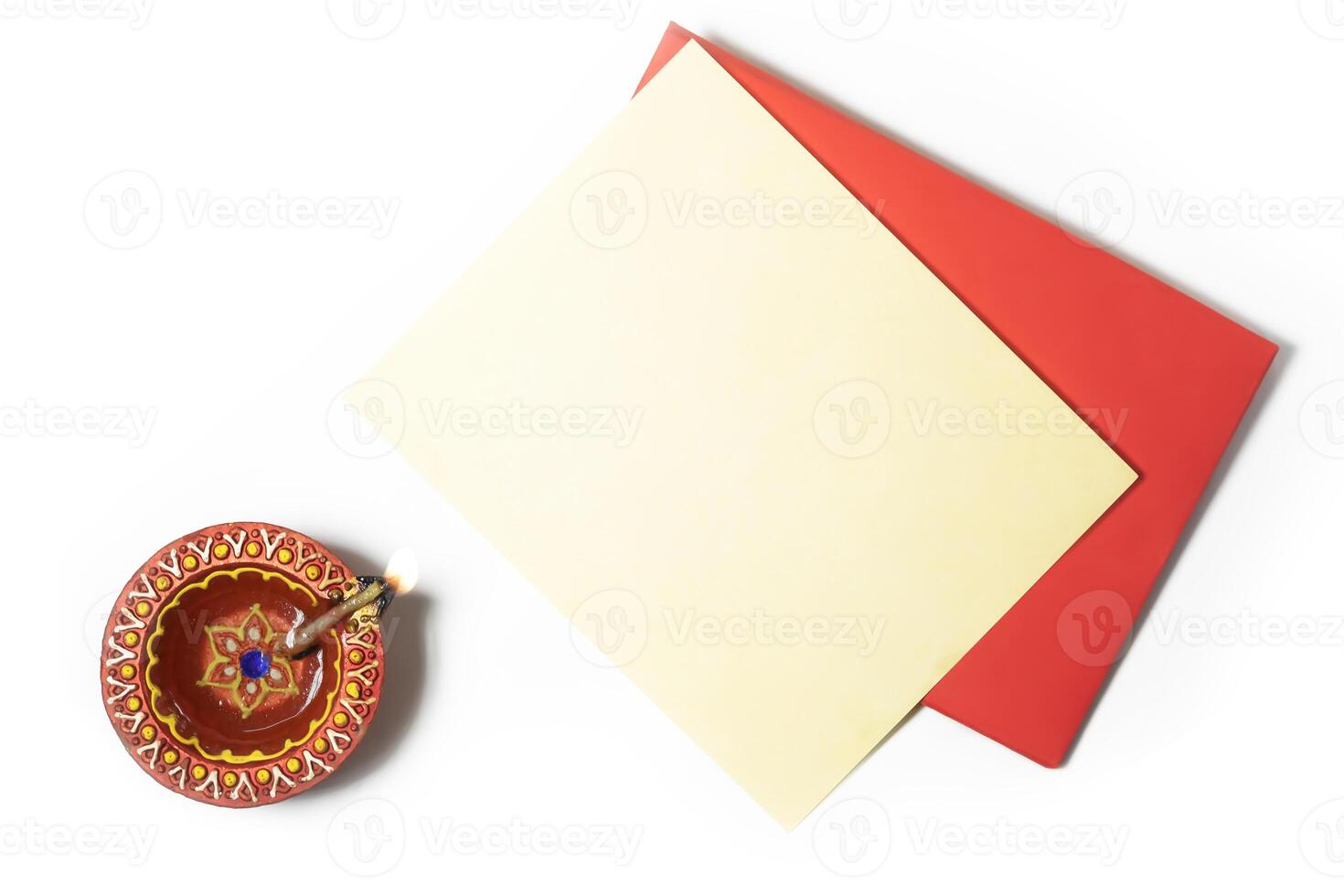 Red envelope with blank yellow paper sheets and burning clay oil lamps on white background to wish Diwali festival photo