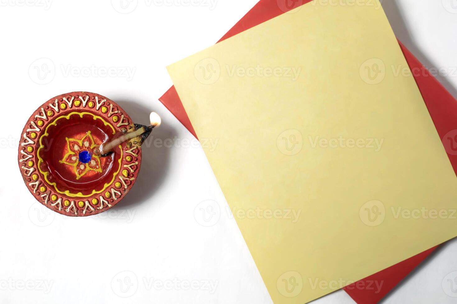 Burning clay diya lamp with greeting card on white background to wish Diwali festival celebration. photo