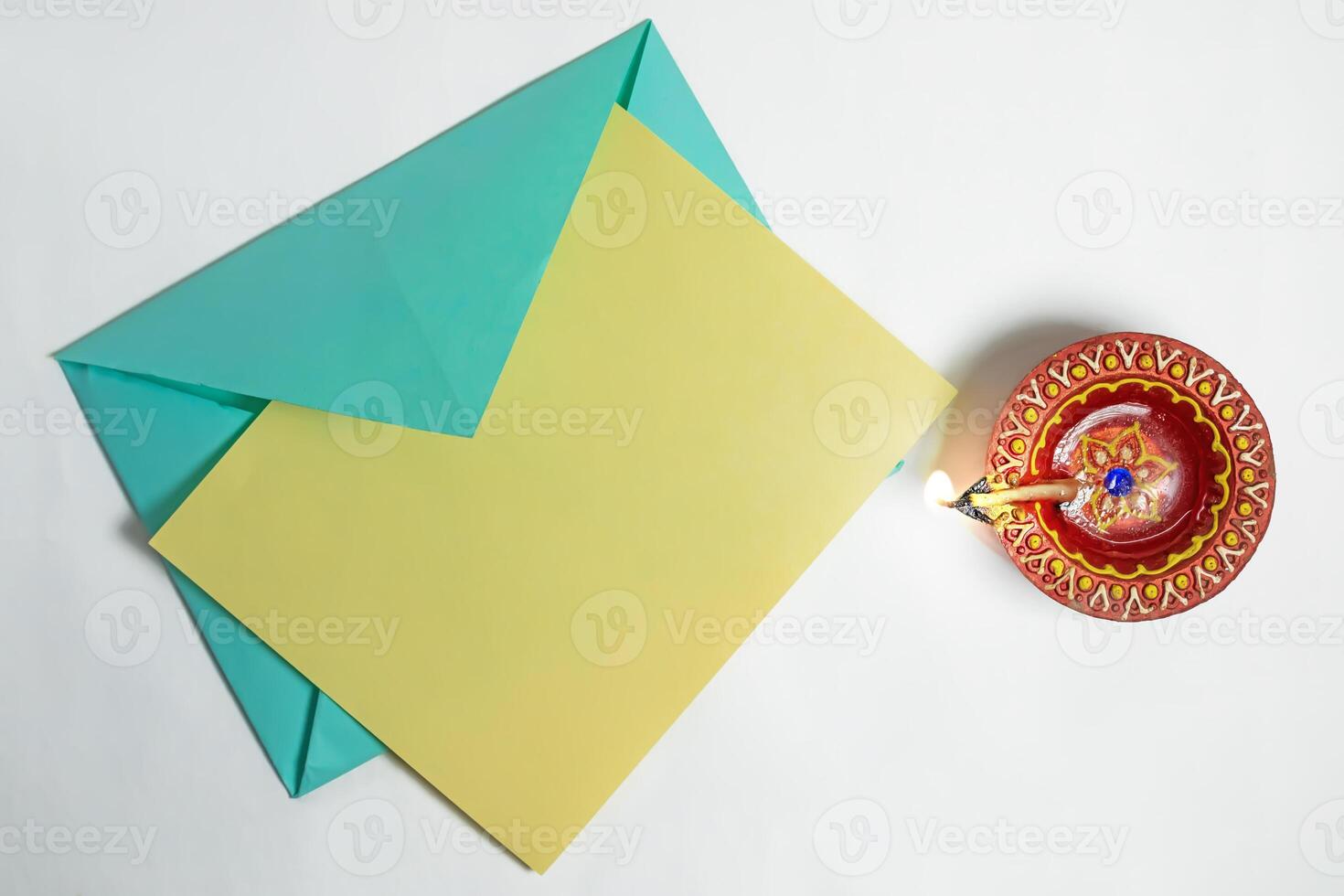 Burning clay diya lamp with greeting card on white background to wish Diwali festival celebration. photo