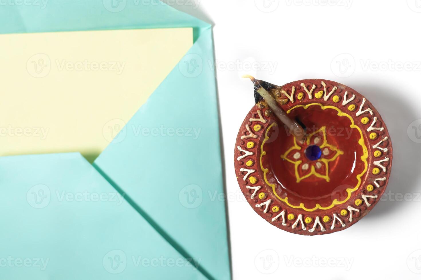 Diwali lit diya lamp and envelope on white background. Diwali concept. photo
