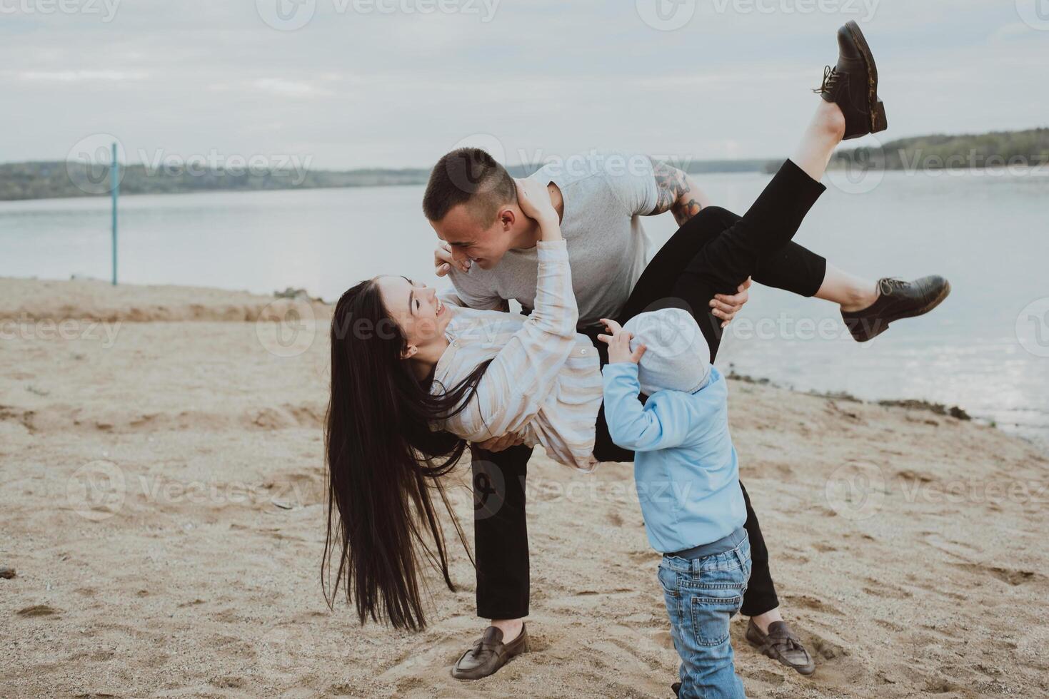 Young happy family having fun on the sand on the beach photo