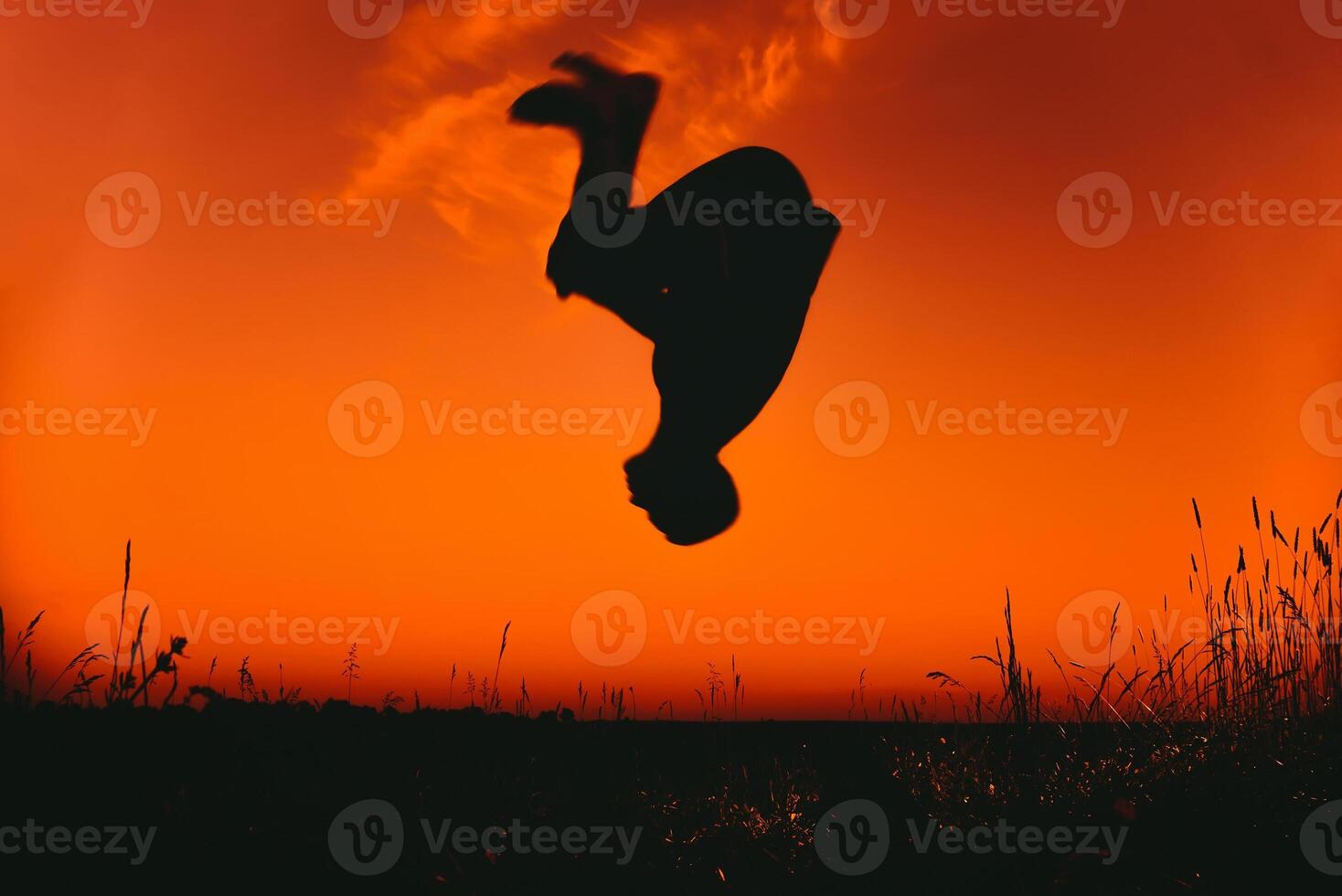 man performs an element of parkour. Silhouette doing a somersault at sunset outdoors photo