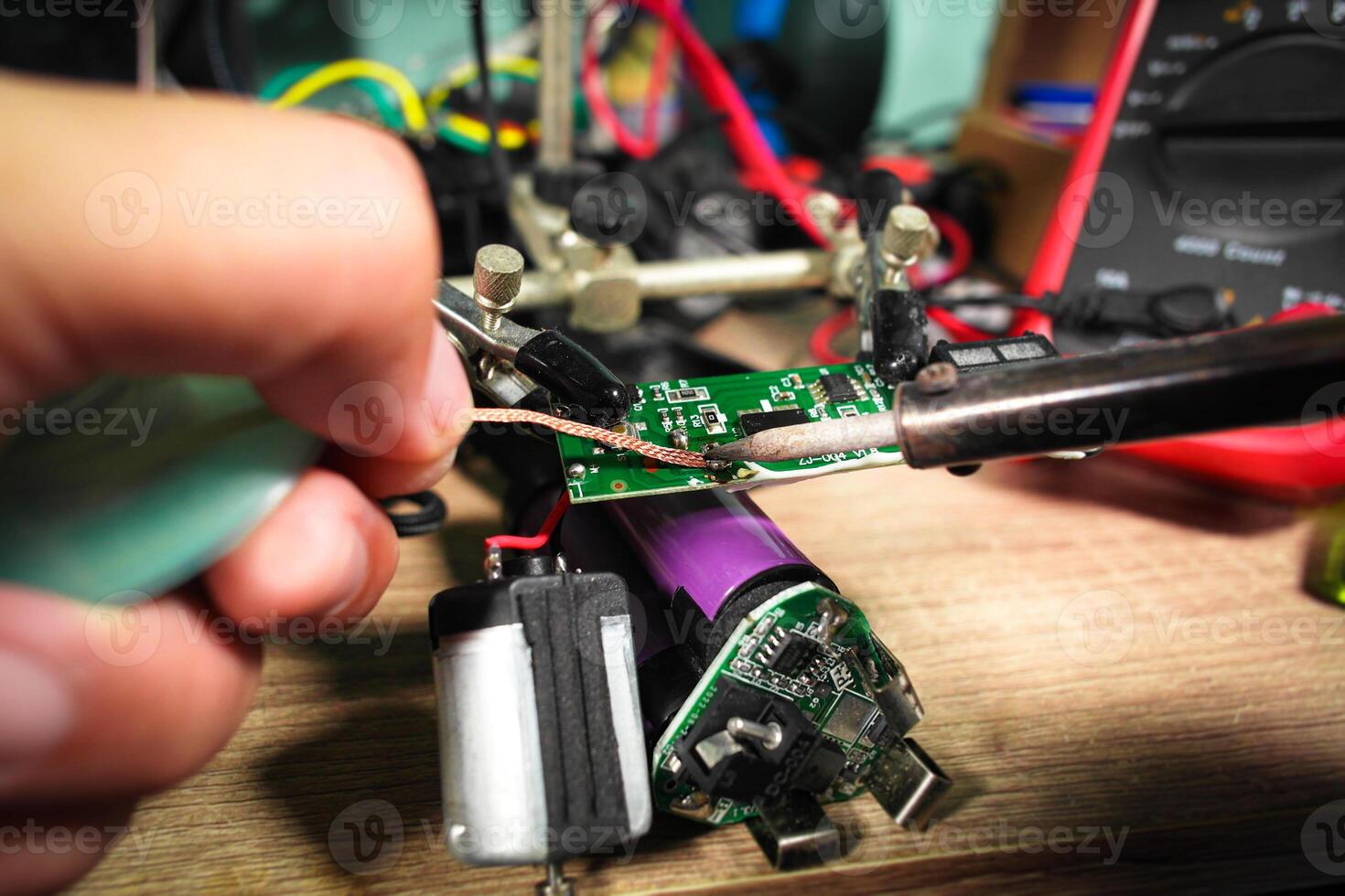 The extraction of lead using desoldering wire or solder wick and soldering iron by an electrician to repair an electronic circuit board , Electric appliance repair concept photo