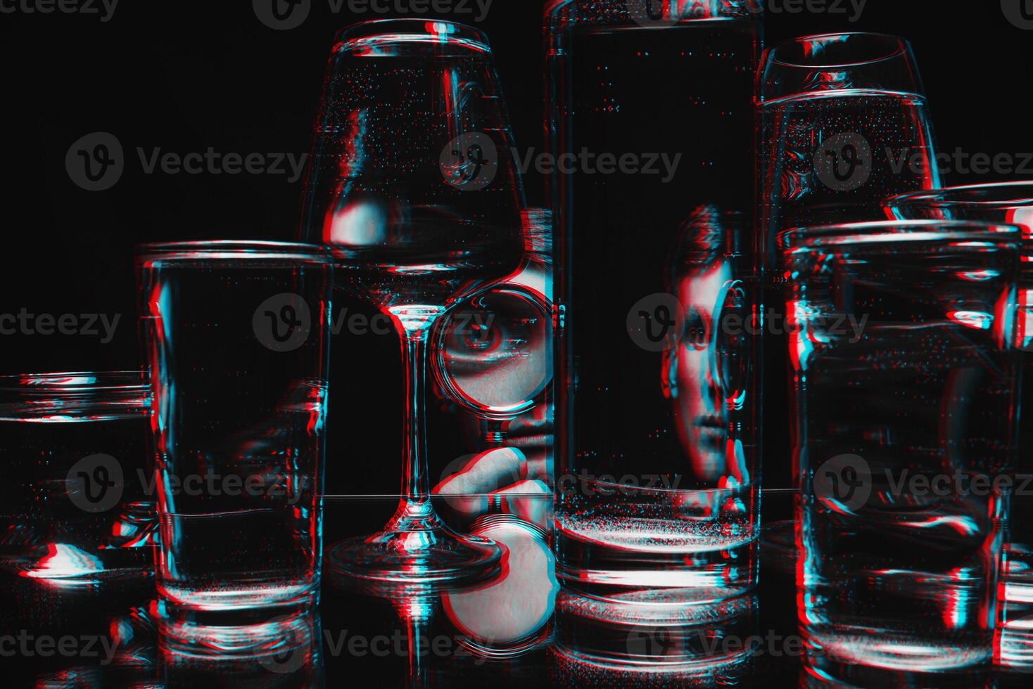 man looking through a magnifying glass and glasses of water with reflections and distortions photo