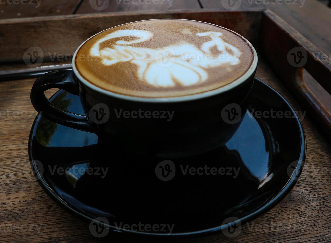 Close up black coffee cup with latte art on wood tab photo