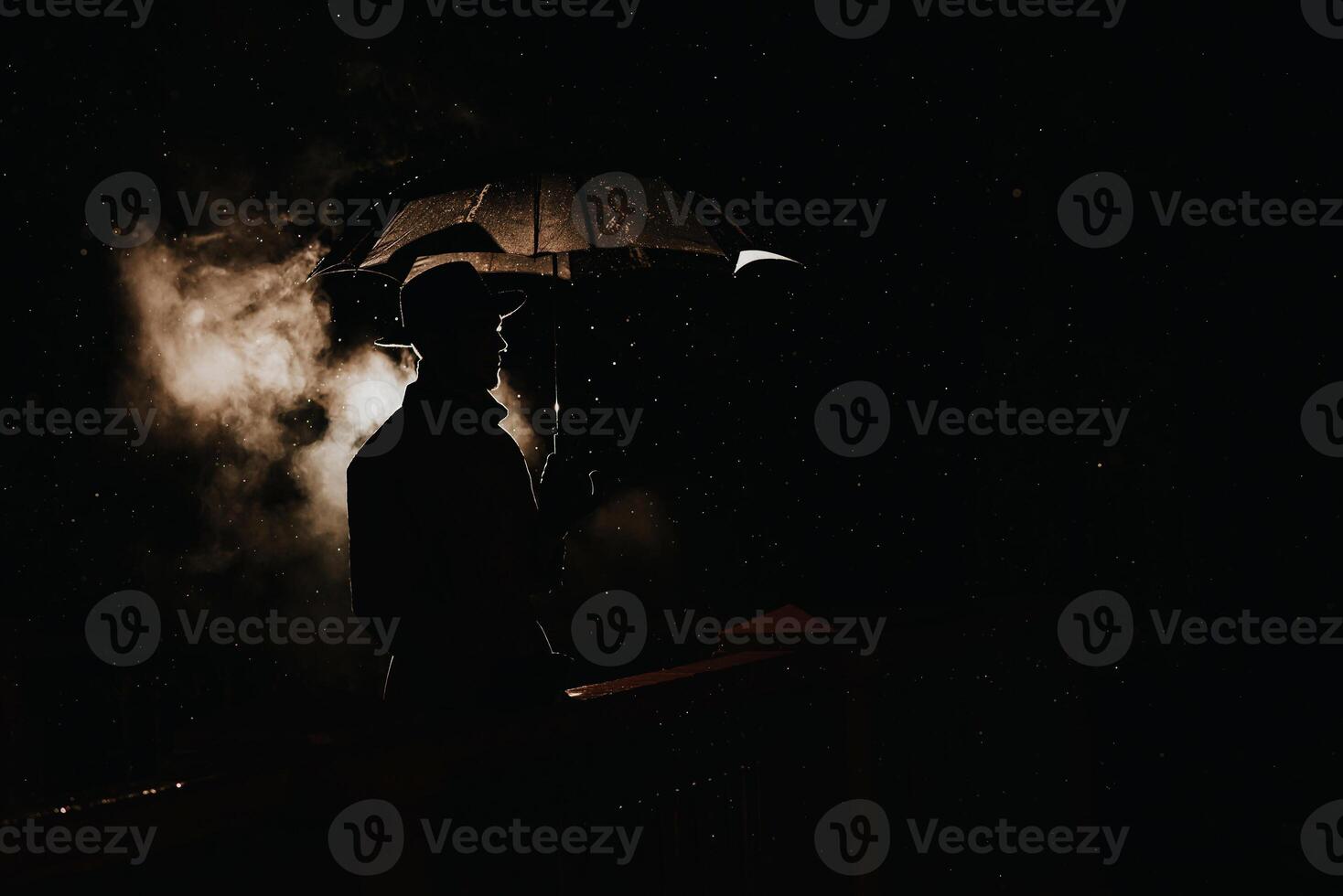 silhouette in the noir style of a male mafia detective in a raincoat and hat under an umbrella photo