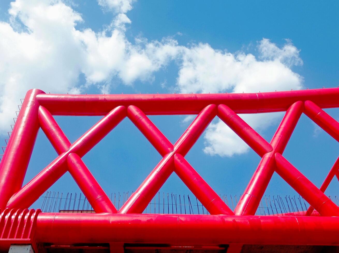 construction of the Indonesian railway bridge. a red structure with a blue sky and clouds photo