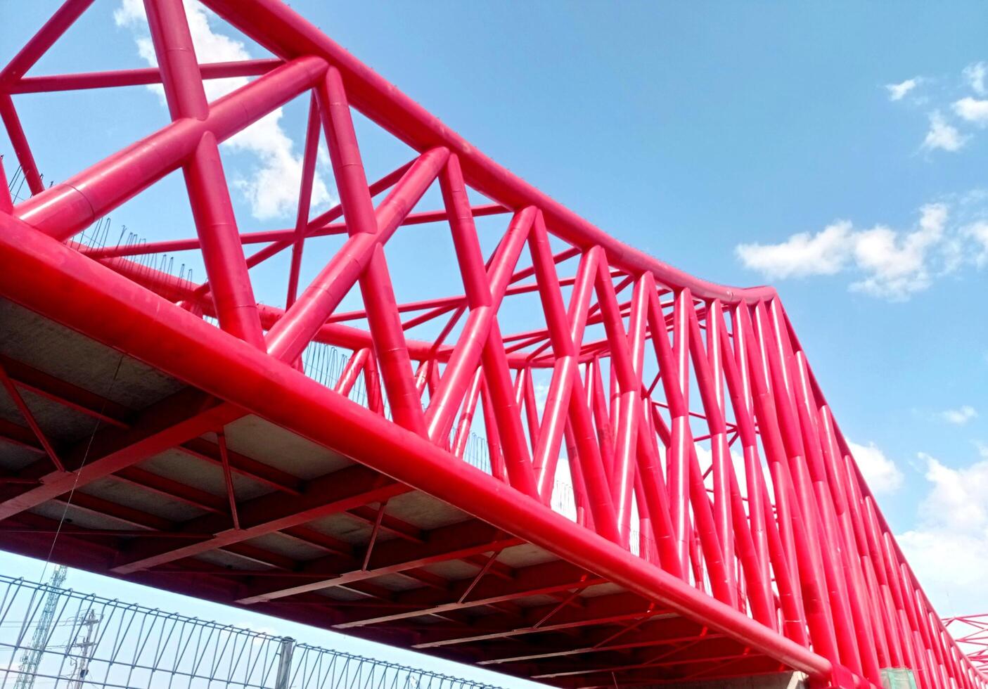 construction of the Indonesian railway bridge. a red structure with a blue sky and clouds photo