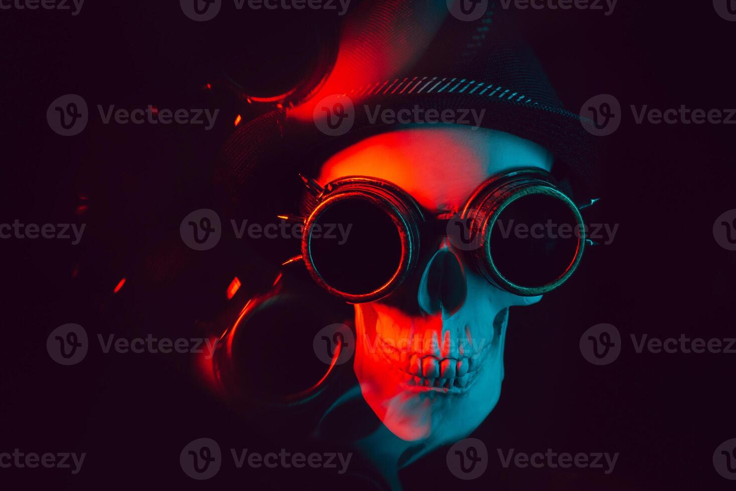 human skull in steampunk glasses and a hat on a dark background with reflection photo