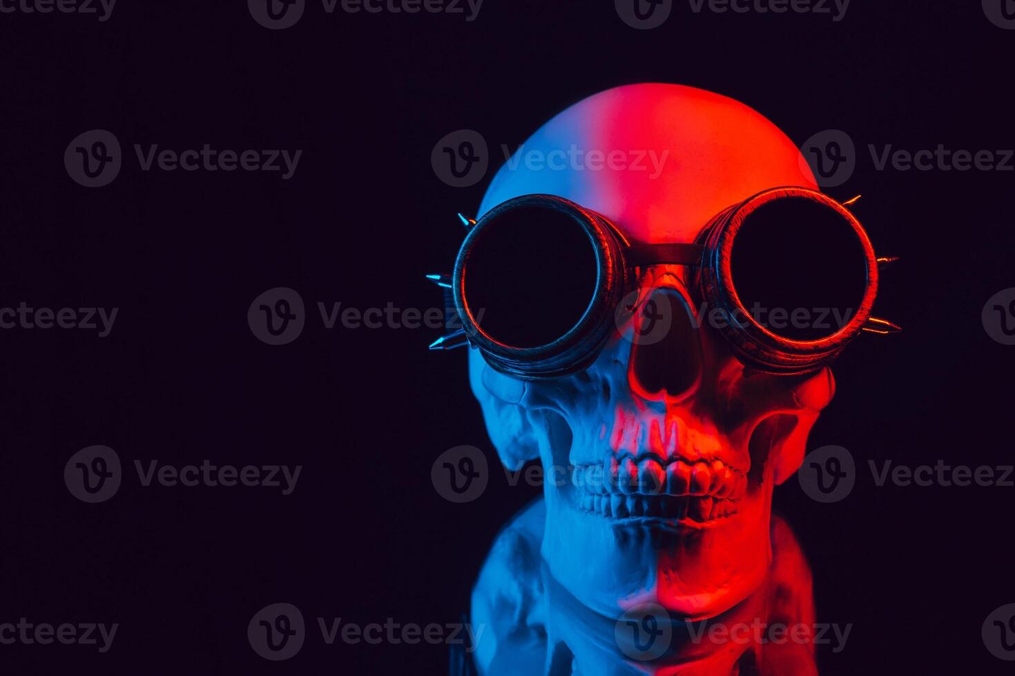 human skull in steampunk glasses with mirror reflection with colored neon light photo