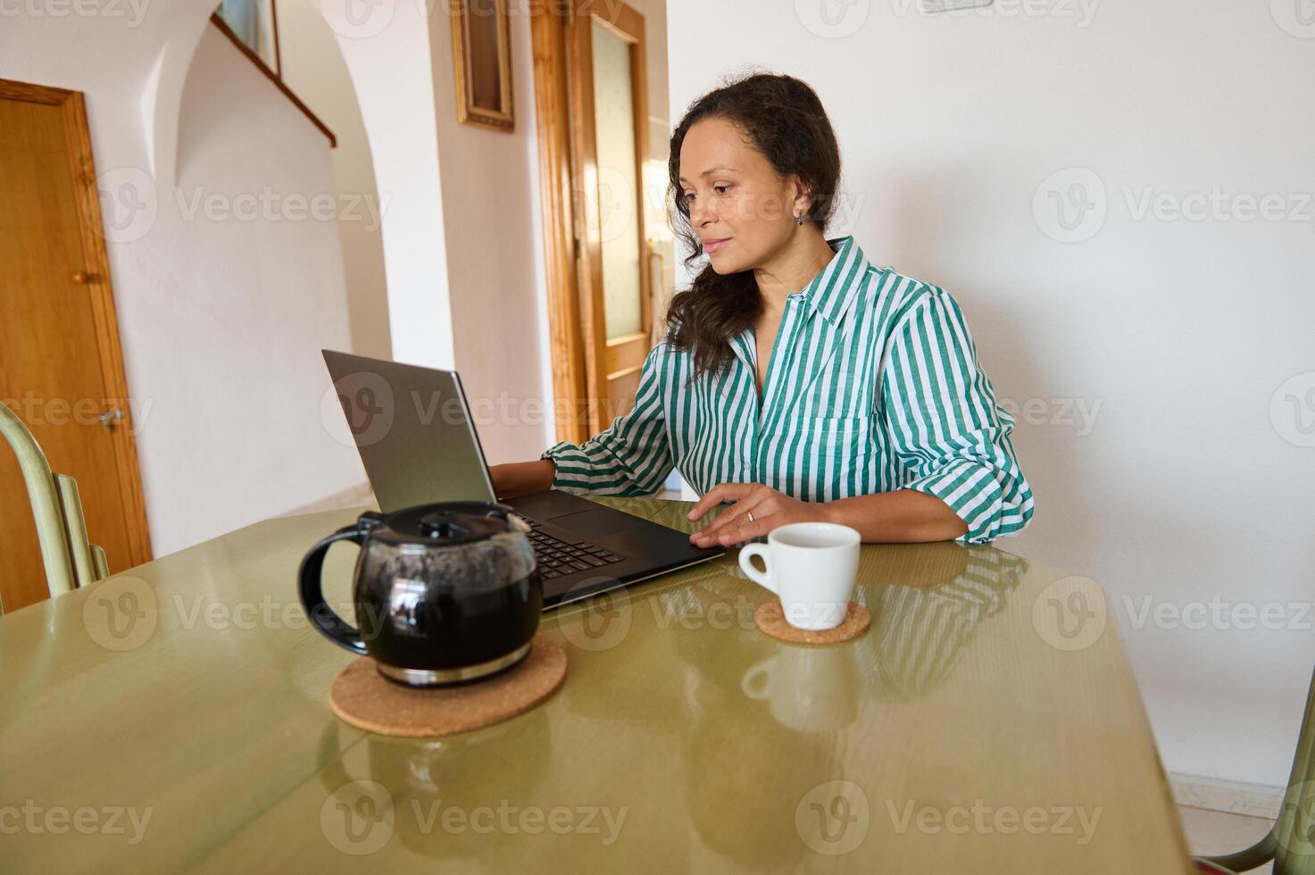 Woman working from home with laptop and coffee on table photo