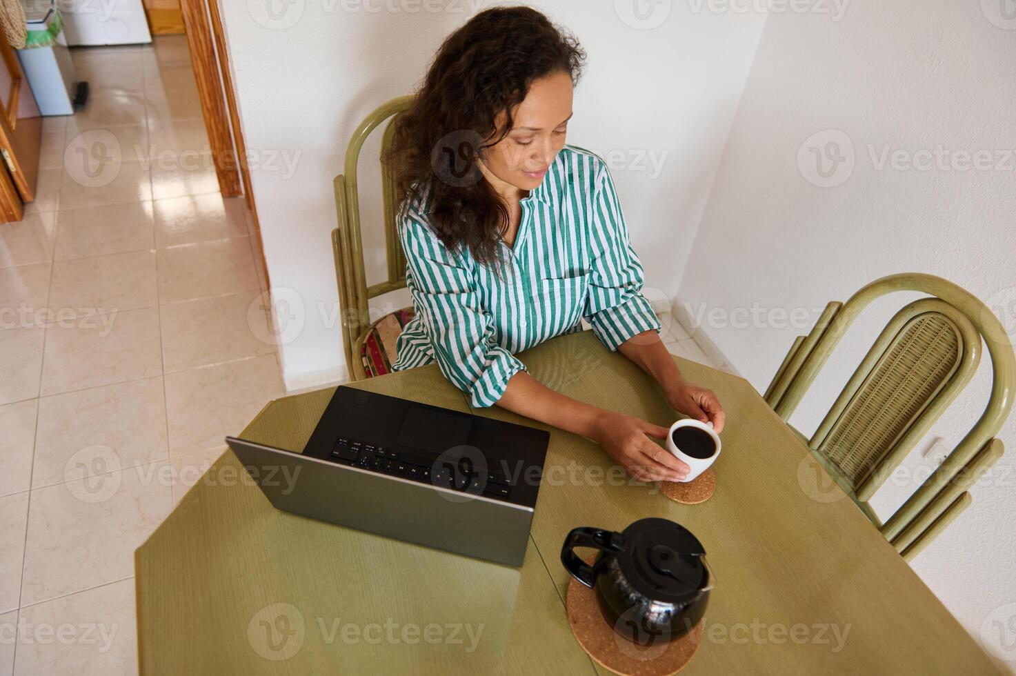 Woman enjoying coffee while working from home at table photo