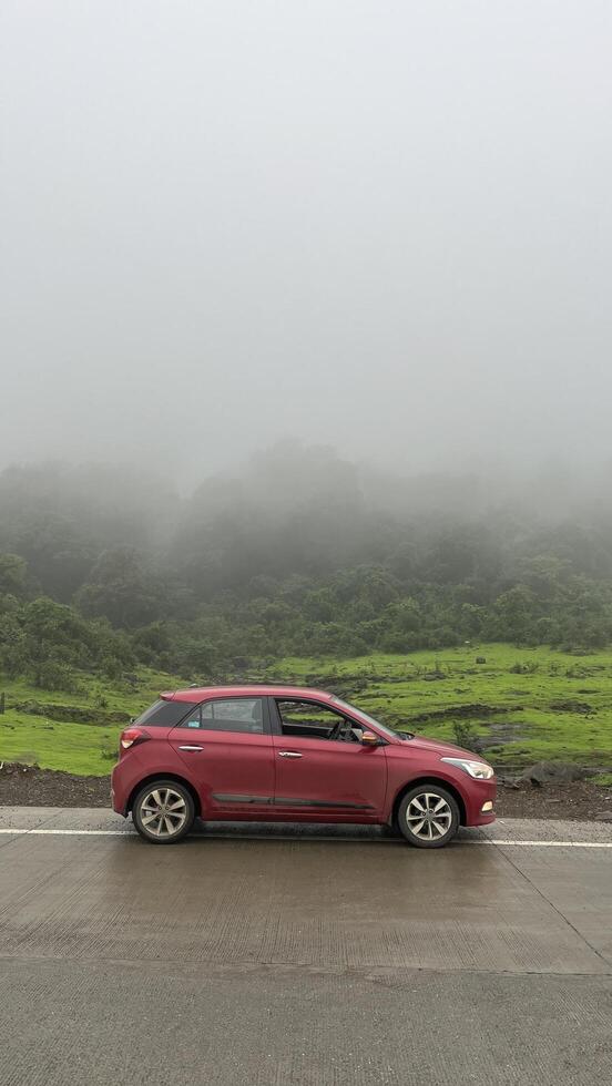 A red car parked against mountain mist fog photo