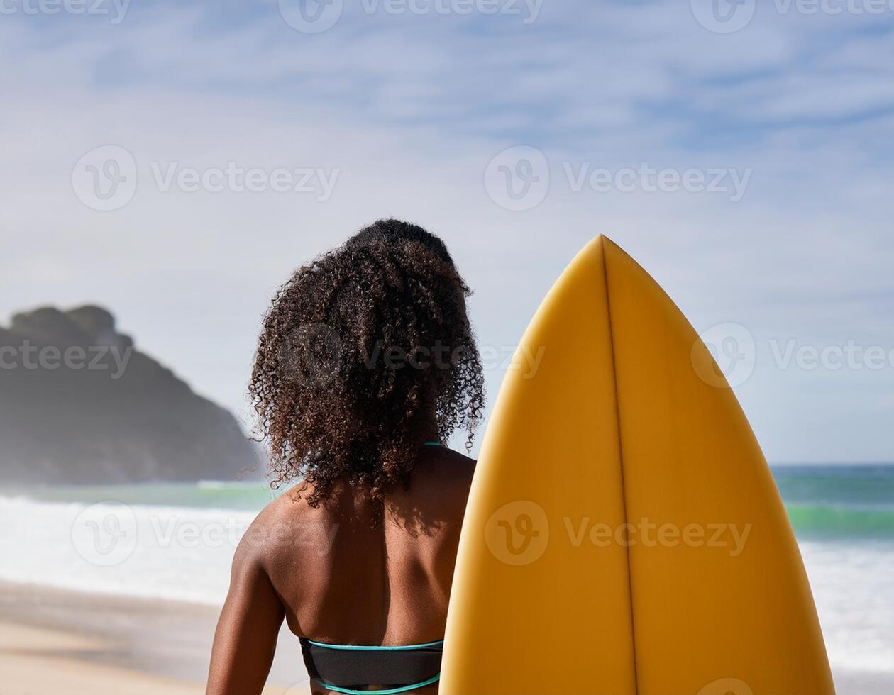 portrait of a black female surfer with her back in the foreground and the beach in the background photo