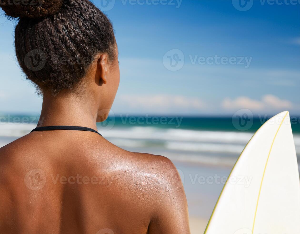 portrait of a black female surfer with her back in the foreground and the beach in the background photo