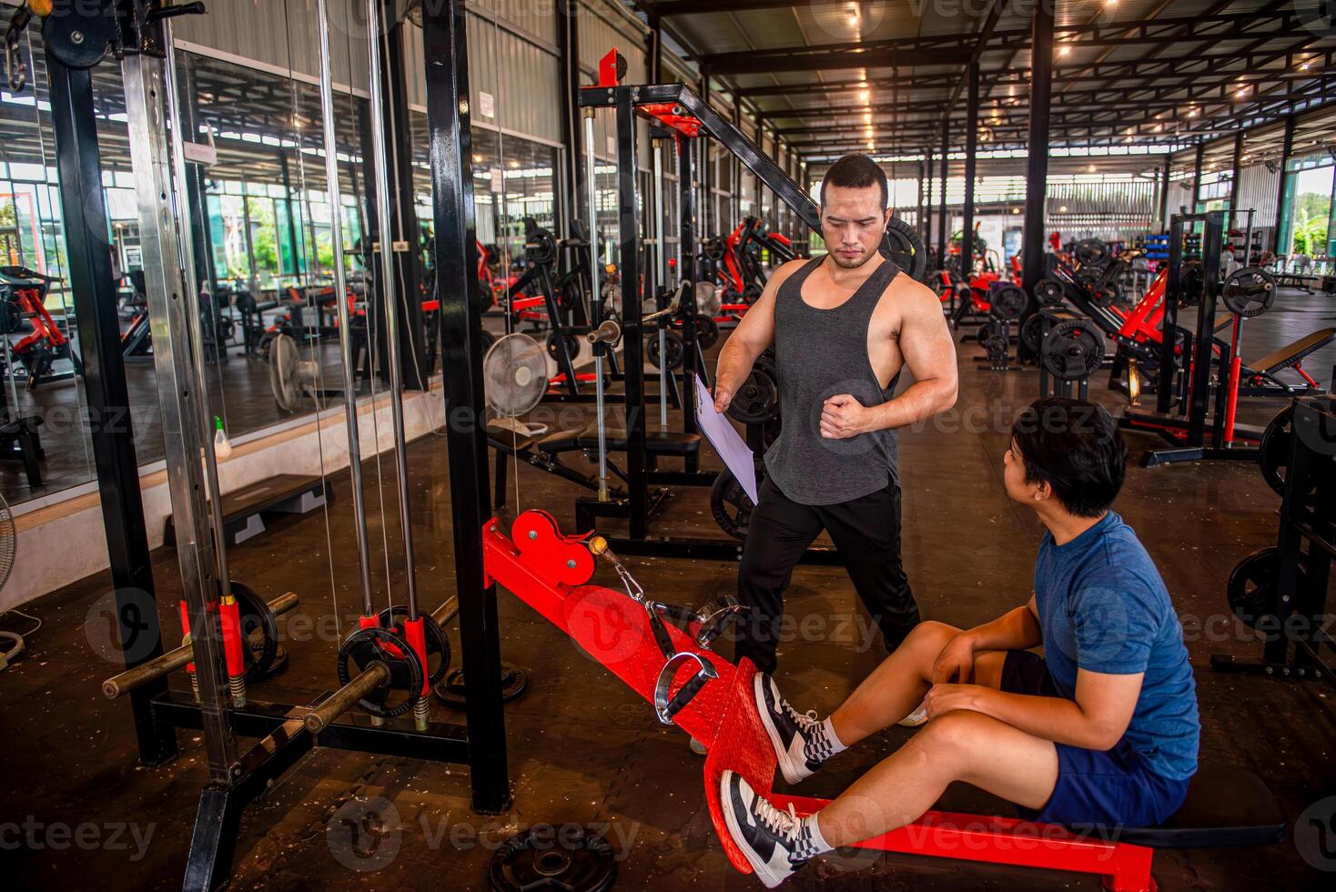 Male trainer teaching trainees the correct posture for using exercise equipment at the gym photo