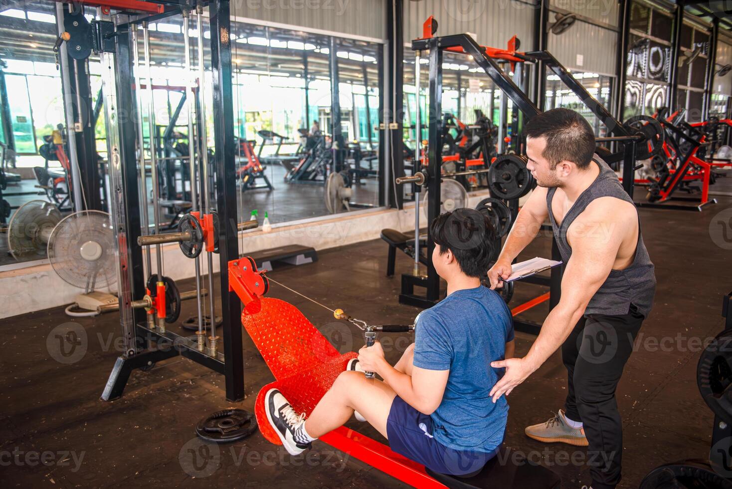 Male trainer teaching trainees the correct posture for using exercise equipment at the gym photo