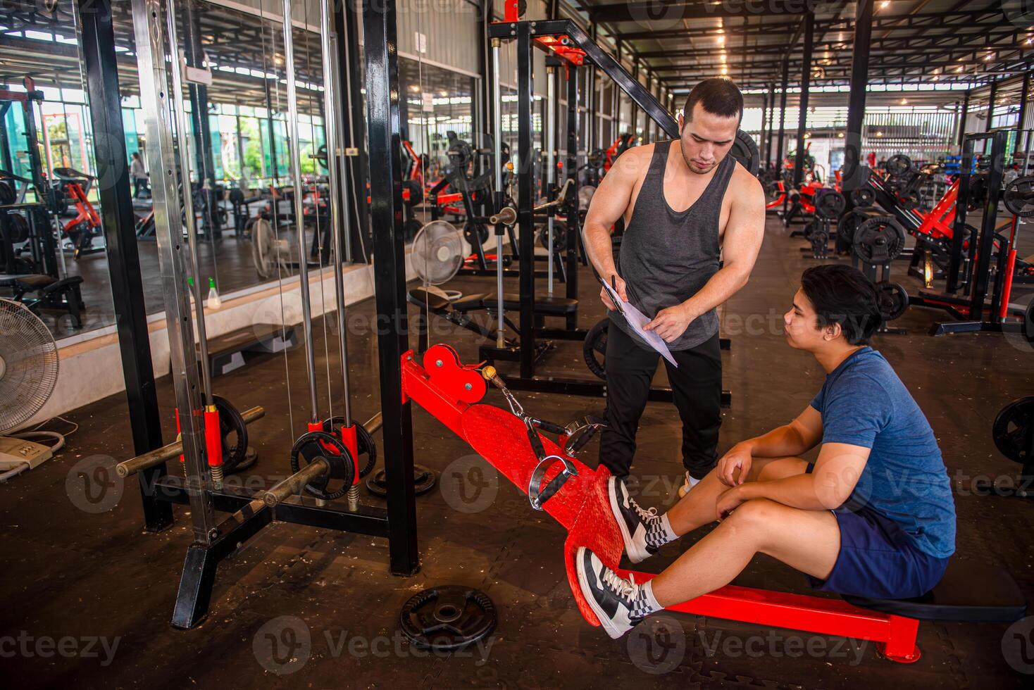 Male trainer shows the exercise program to the trainee and plans the exercise plan for the trainee. photo