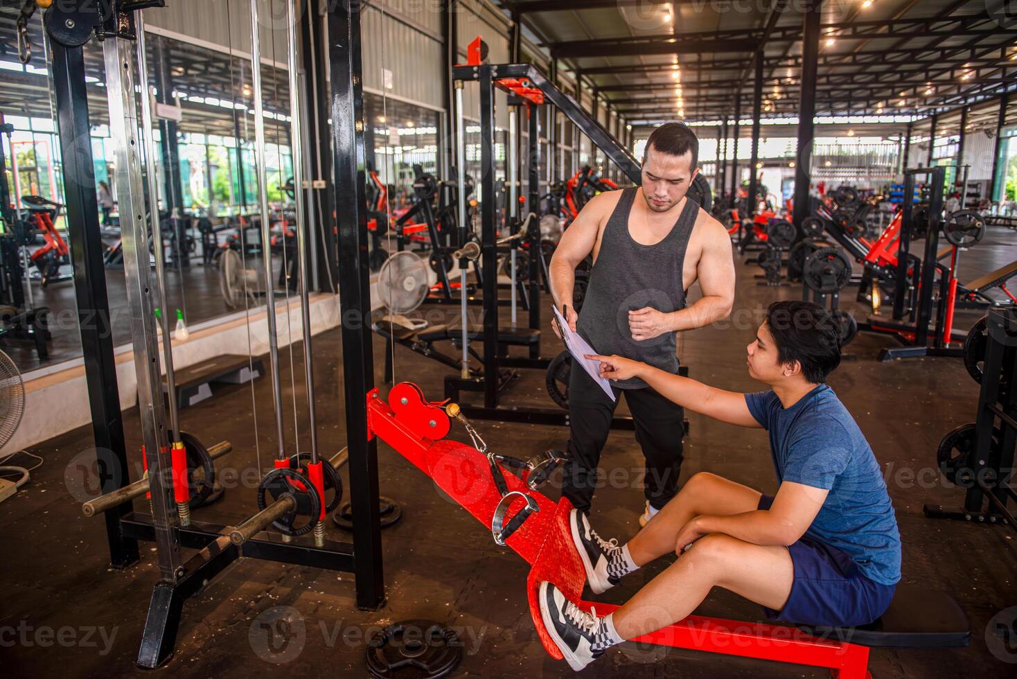 Male trainer shows the exercise program to the trainee and plans the exercise plan for the trainee. photo