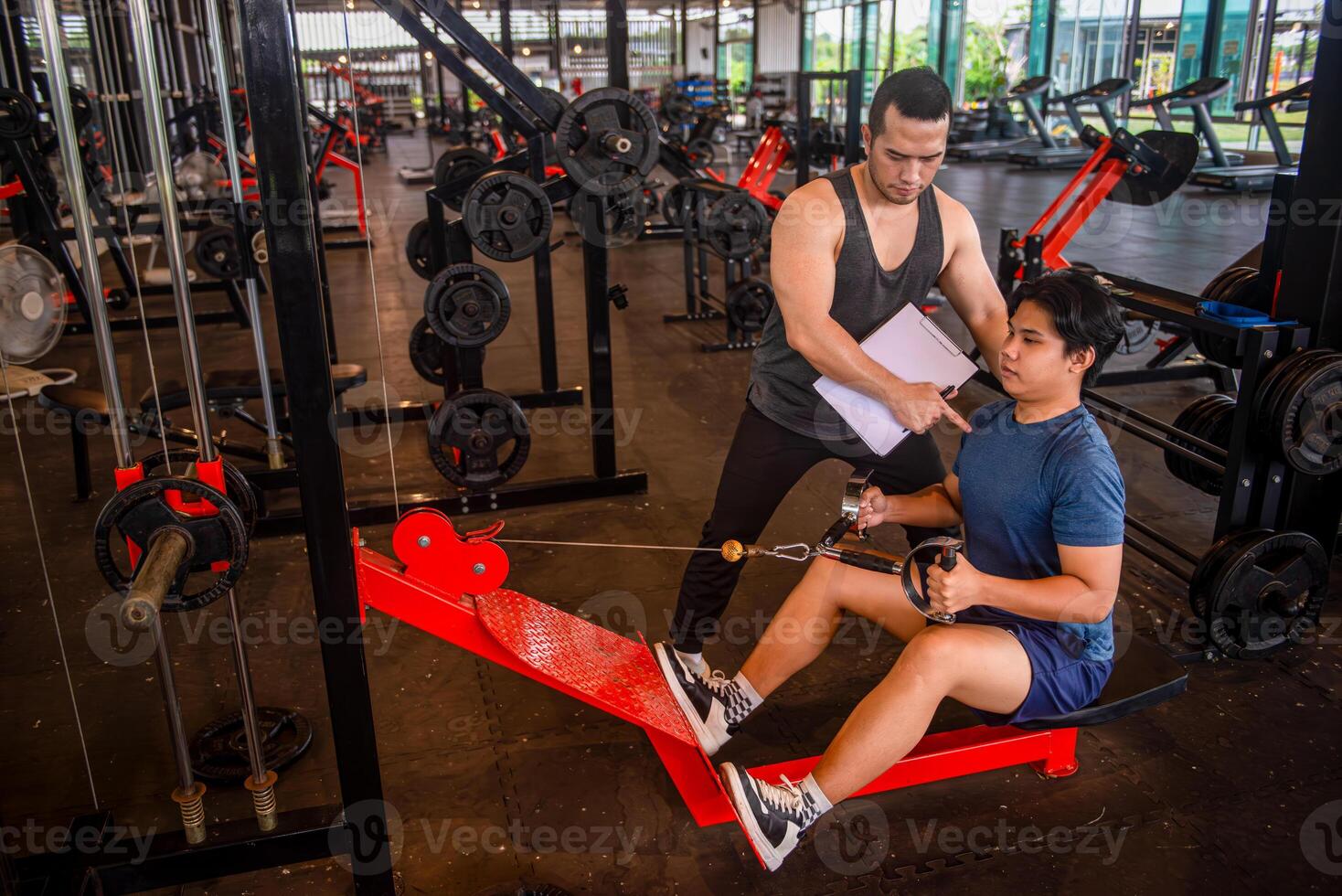 Male trainer teaching trainees the correct posture for using exercise equipment at the gym photo