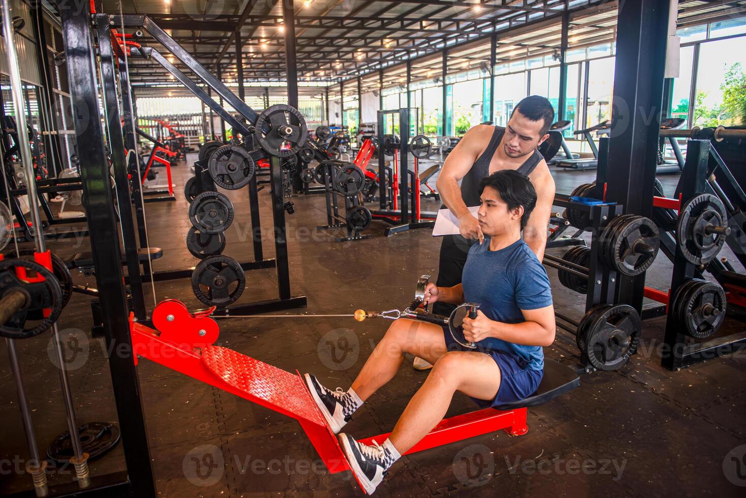Male trainer teaching trainees the correct posture for using exercise equipment at the gym photo
