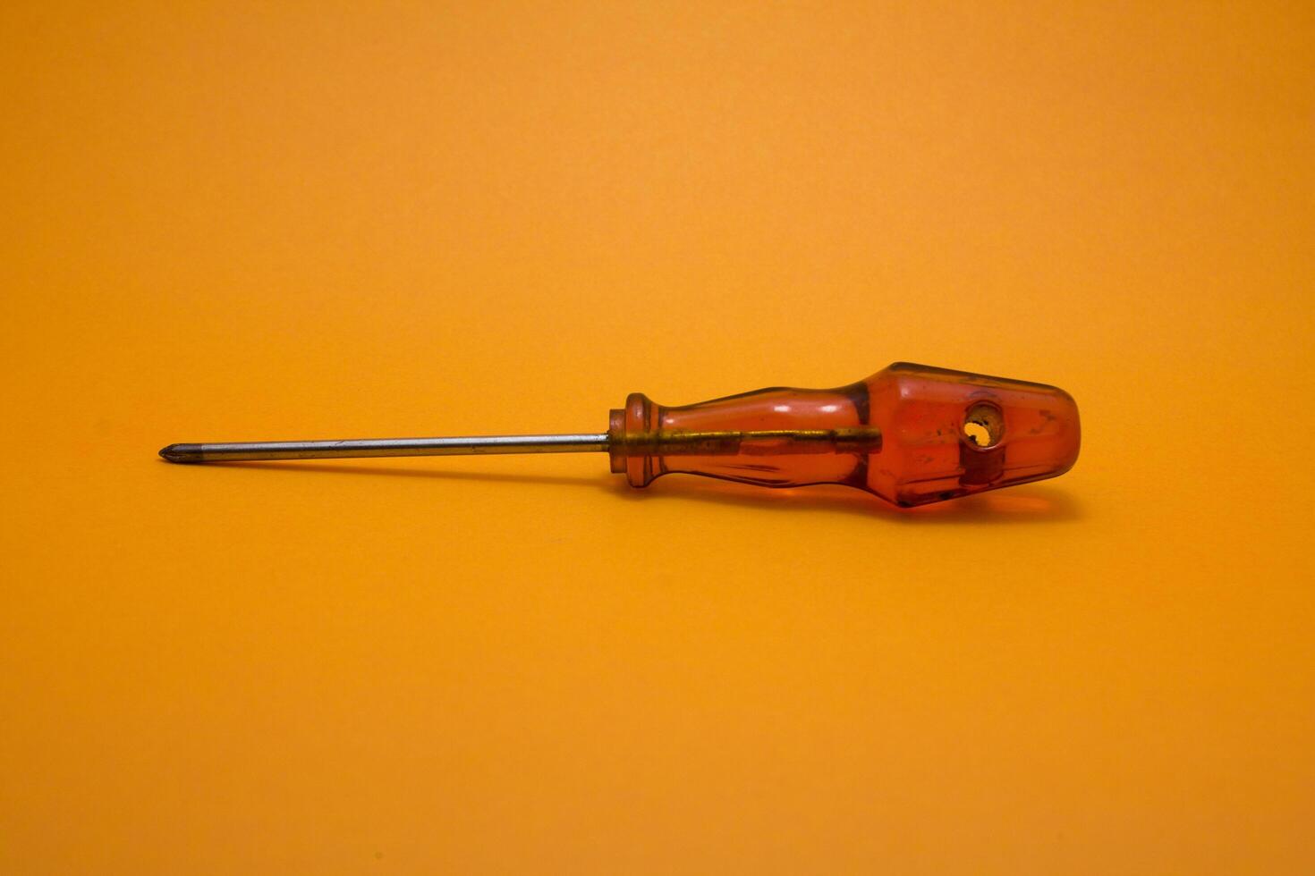 a red handle screwdriver isolated on yellow background photo