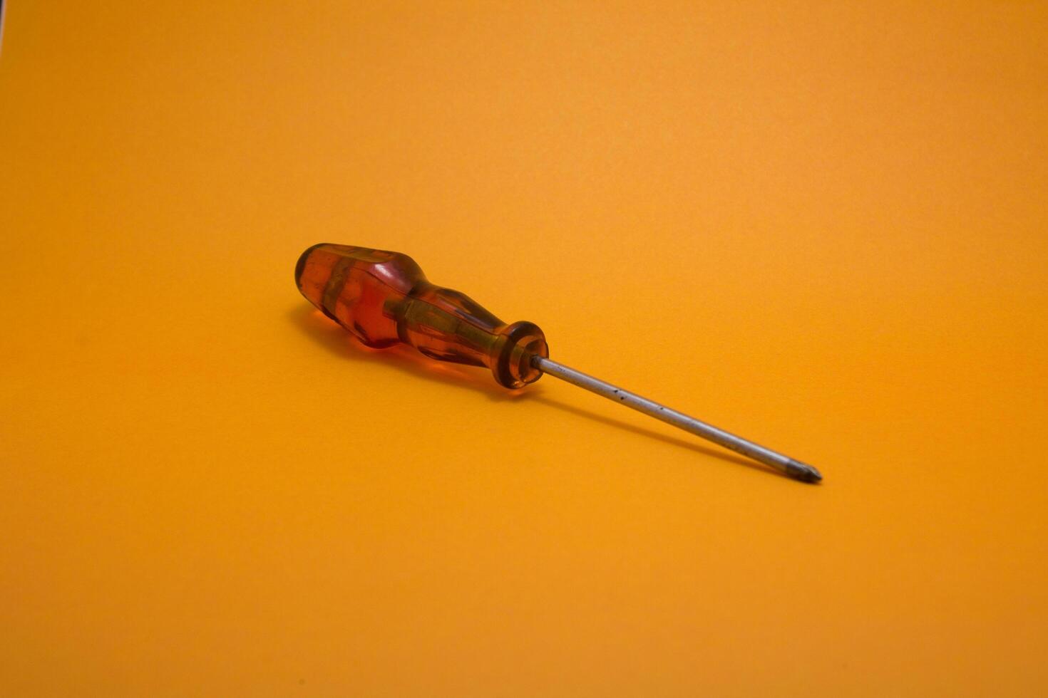 a red handle screwdriver isolated on yellow background photo