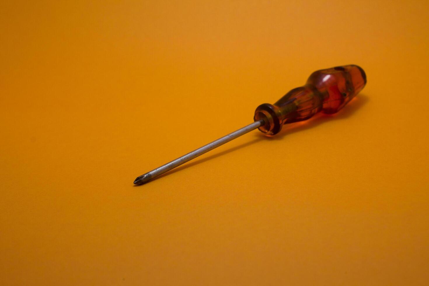 a red handle screwdriver isolated on yellow background photo