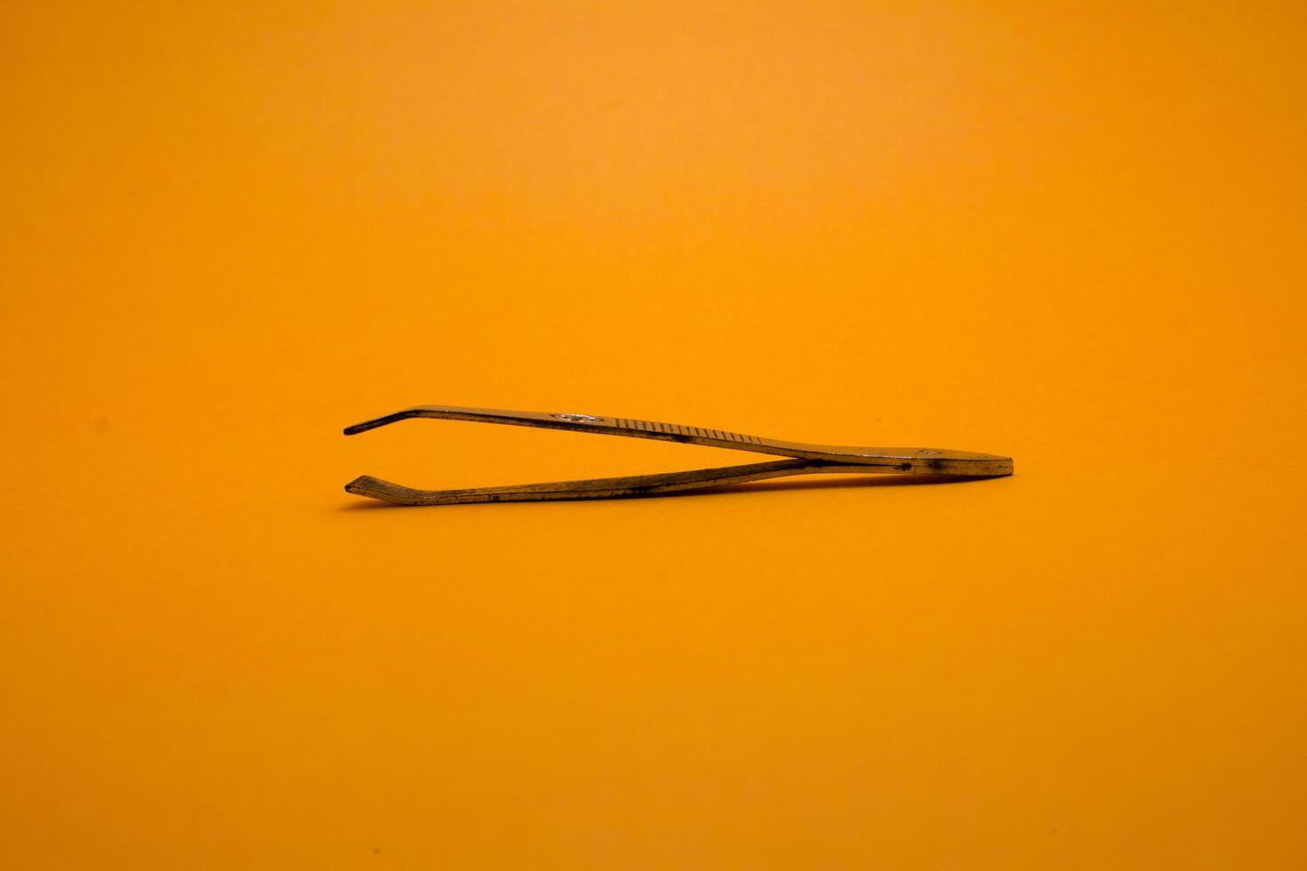 tweezers isolated on yellow background photo